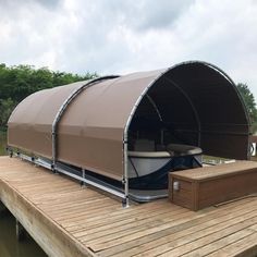 a boat sitting on top of a wooden dock next to a large canopy over it