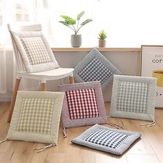 four different cushions sitting on the floor in front of a chair and coffee pot holder