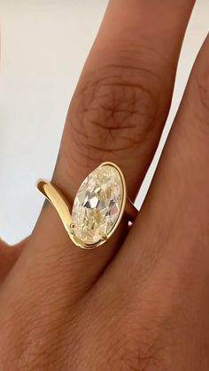 a woman's hand with a yellow diamond ring on top of her finger,