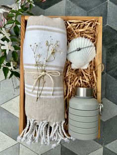 a wooden box with towels, a bottle and a vase on the floor next to it