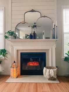 a fire place in a living room with a mirror above it and candles on the mantle