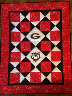 a red and black quilted table topper with a college logo on the center