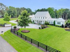 an aerial view of a large white house in the middle of a lush green yard