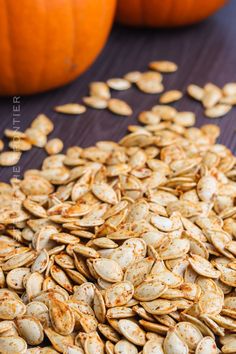 pumpkin seeds on a wooden surface next to oranges