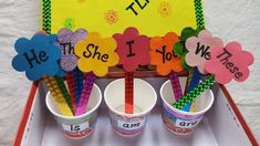 three cups filled with paper flowers on top of a table