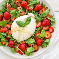 a white plate topped with spinach and strawberries