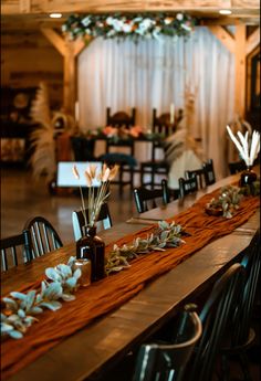 the table is set up for an event with flowers and greenery in vases