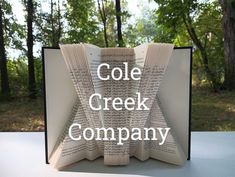 an open book with the words cole creek company printed on it and trees in the background