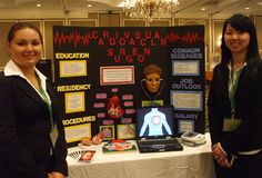 two women standing next to a table with information on it