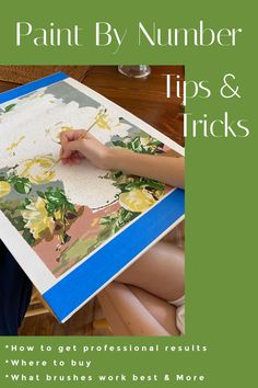 a woman sitting on the floor painting flowers with paint by number tips and tricks