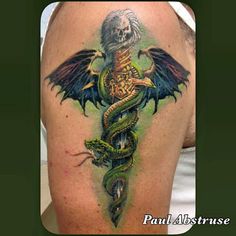 a woman with a tattoo on her back has a dragon and snake on it's shoulder