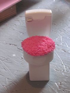 a white toilet with pink rugs on the seat and tank cover in front of it