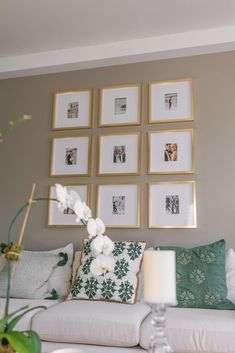 a living room with pictures on the wall and flowers in vases next to it