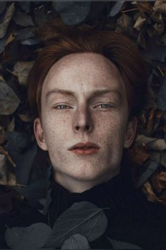 a man with freckles on his face laying in leaves