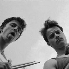 two young men standing next to each other with their mouths open and one holding a baseball bat