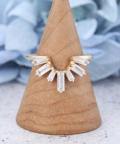 a gold ring with clear stones on top of it in front of a wooden cone