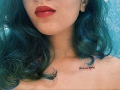 a woman with green hair has a tattoo on her chest