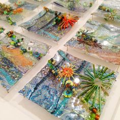 several square pieces of art made out of glass and beaded with beads on them