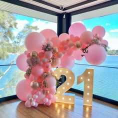 balloons and lights are arranged on the floor in front of a window that overlooks water