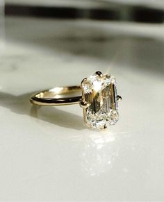 an engagement ring with a large diamond in the center on a white surface, close up