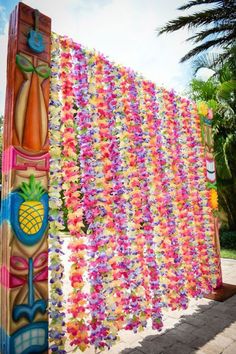 a colorfully decorated wooden pole with flowers and pineapples hanging from it's sides