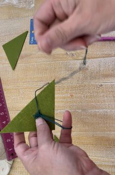 someone is making a paper christmas tree ornament out of green felt and twine