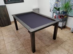 a pool table sitting on top of a tiled floor next to a potted plant