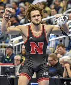 two men in wrestling uniforms with their hands up