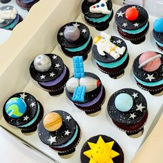 a box filled with cupcakes covered in space themed icing