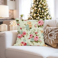 a living room with a christmas tree in the background and flowers on the pillow cover