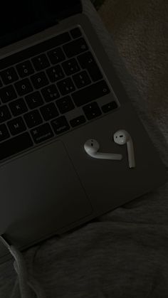 an open laptop computer sitting on top of a bed next to a pair of headphones