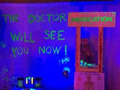 the doctor will see you now on display in front of a neon purple wall with green writing