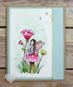 a handmade card with a fairy sitting on top of a mushroom and pink flowers