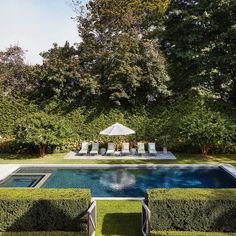 an outdoor swimming pool surrounded by hedges and trees