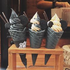 three ice cream cones sitting on top of a wooden table