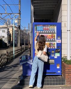 a woman standing in front of a vending machine on the side of a road