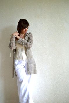 a woman standing in front of a wall with her hands on her hips and wearing white pants