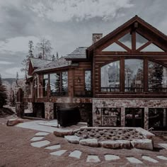 a large house with a stone fire pit in front of it and lots of windows