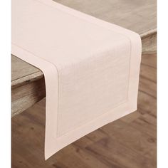 a table with a white linen runner on it and wood flooring in the background