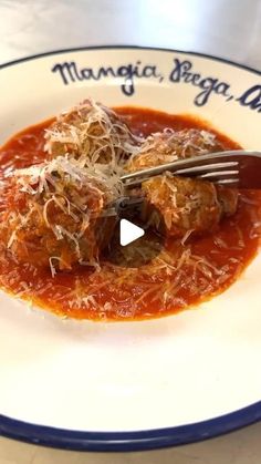 a white plate topped with meatballs covered in sauce and grated parmesan cheese