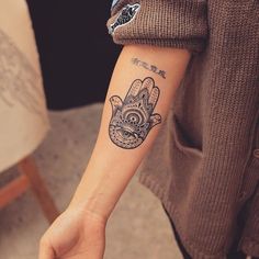 a person with a tattoo on their arm and hand holding something in the other hand