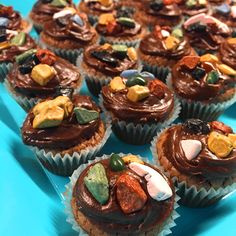 cupcakes with chocolate frosting and colorful toppings on blue paper wrappers