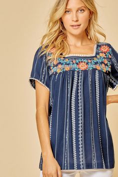 A beautiful top with summer-to-fall versatility. Navy Stripe Embroidered top with round Neckline Neckline has pom pom detail Flowy Fit & Non Sheer Rayon Blue Tassel Tops For Summer, Spring Short Sleeve Tops With Contrast Embroidery, Spring Tops With Contrast Embroidery And Short Sleeves, Short Sleeve Tops With Contrast Embroidery For Spring, Spring Vacation Embroidered Top With Embroidered Neckline, Spring Vacation Embroidered Neckline Top, Spring Vacation Embroidered Top With Embroidered Hem, Spring Vacation Tops With Embroidered Hem, Bohemian Summer Tops With Embroidered Hem