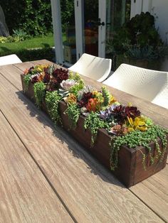 a wooden table topped with lots of different types of flowers and plants growing out of it