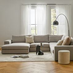 a living room filled with furniture and a large window covered in white drapes next to a wooden floor