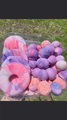 there are many donuts in the plastic container on the table outside with sprinkles