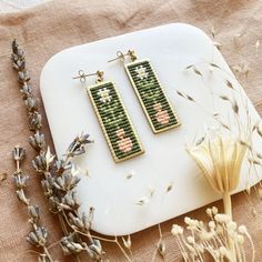 a pair of earrings sitting on top of a table next to dried flowers and plants