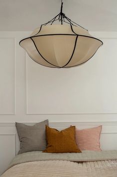 a bed sitting under a light hanging from the ceiling over it's headboard