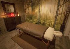 a spa room with a large painting on the wall and a massage table in front of it