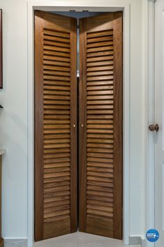 an open wooden door with shutters on the side in a white wall and carpeted floor